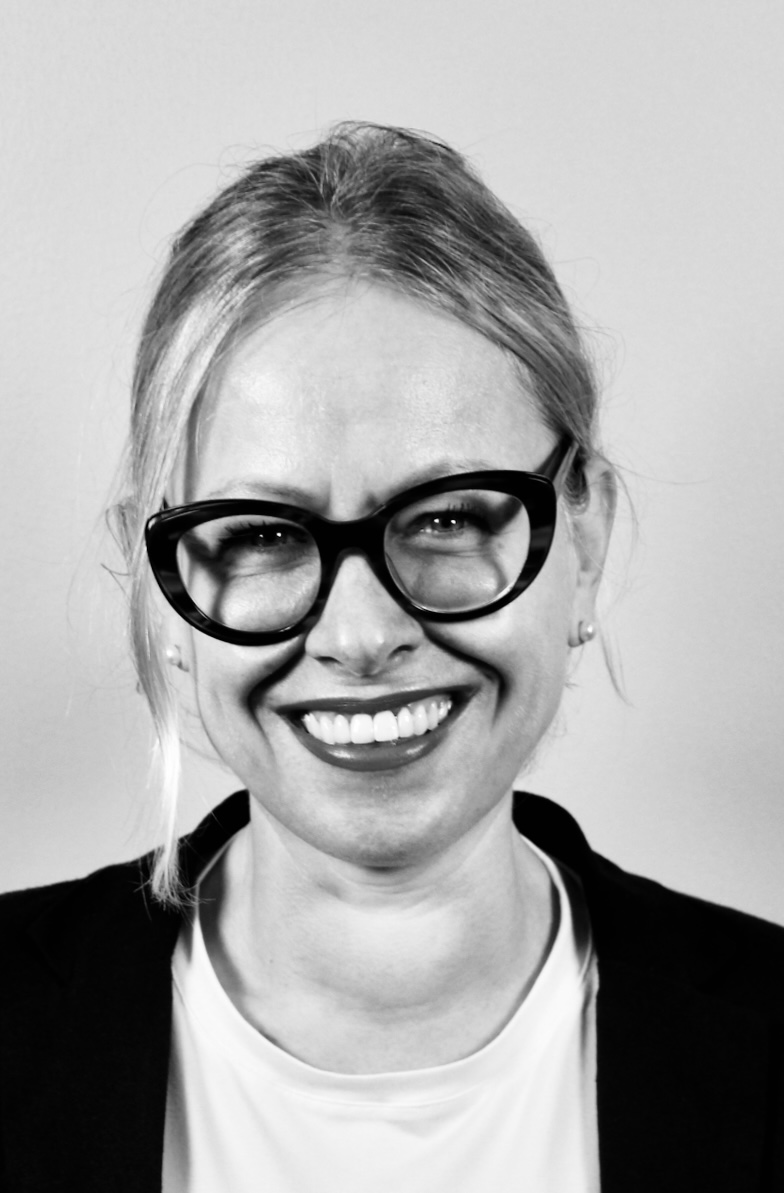Keti Bakiri, founder of Pink Analytica, smiling, wearing glasses and a dark blazer